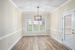 An empty dining room with hardwood floors and a chandelier.