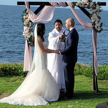 Couple exchanging vows at outdoor wedding ceremony by the ocean.