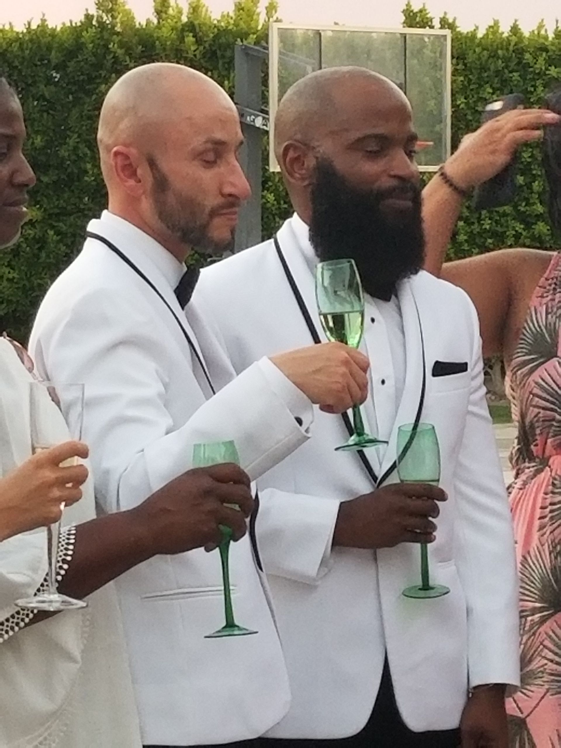 Two Groom toast Champagne glasses with friends after a Palm Springs Wedding Ceremony
