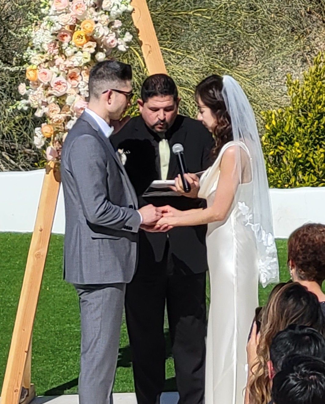 Rev. Steve Pray with a couple in front of a floral decorated A-Frame Arch during their Palm Desert Wedding Ceremony