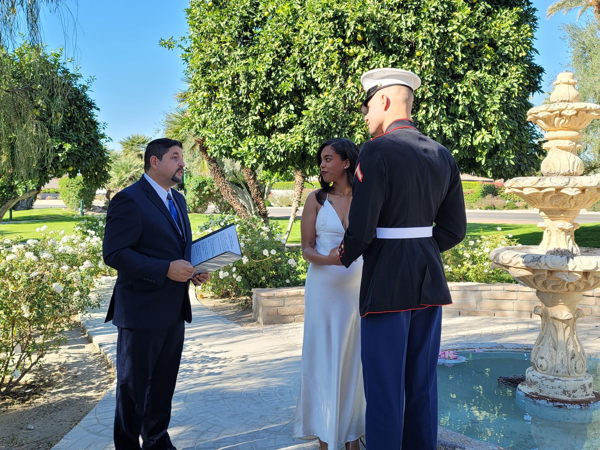 Rev Steve officiates for a Marine Groom and His Bride near a fountain at Wolfson Park in Rancho Mirage, CA