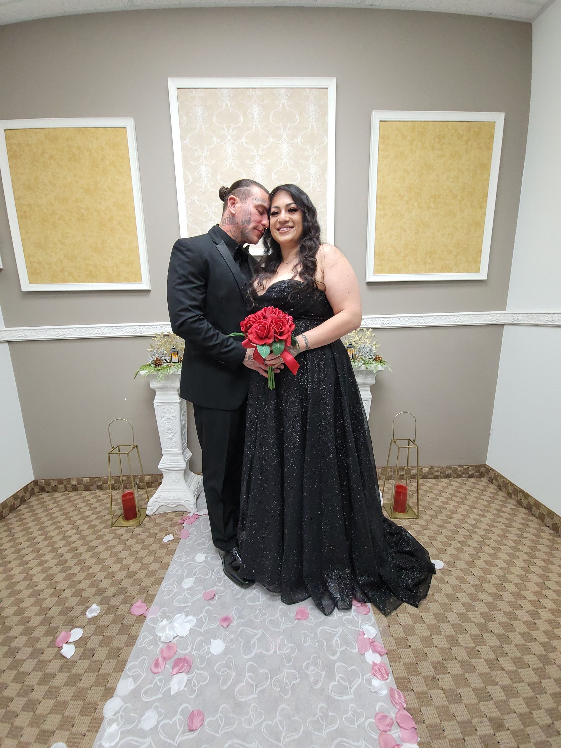Couple in formal wear at a wedding ceremony; bride in black dress, groom in black suit.
