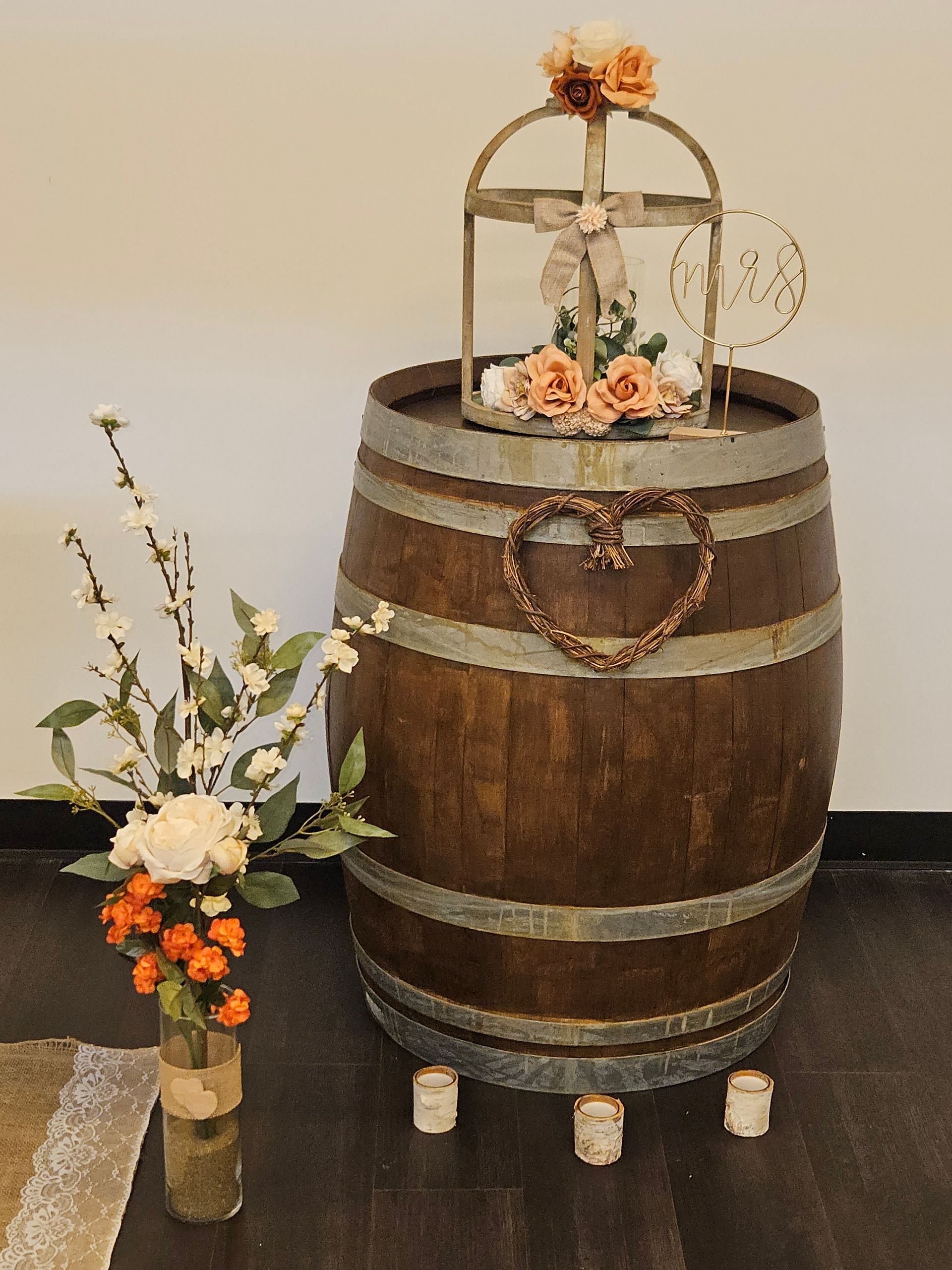 Wooden barrel with floral decorations, candles, and a decorative cage.