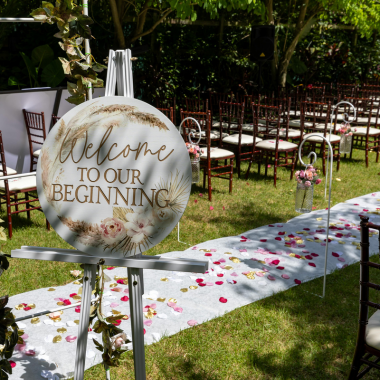 Wedding ceremony setup with welcome sign and aisle decorated with rose petals.
