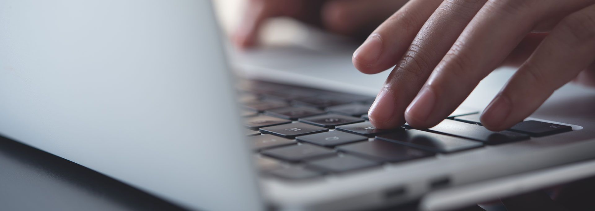 Person's hands typing on a laptop keyboard; close-up shot.