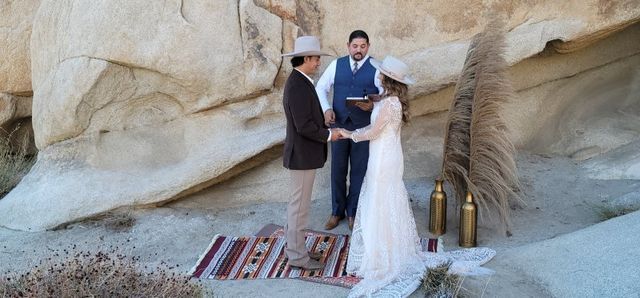 Couple in Cowboy Hats holding hands at their Joshua Tree Ceremony with Rev. Steve