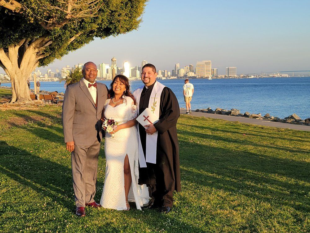 Couple shares a photo with Rev. Steve with Coronado Bay as the backdrop after their ceremony.
