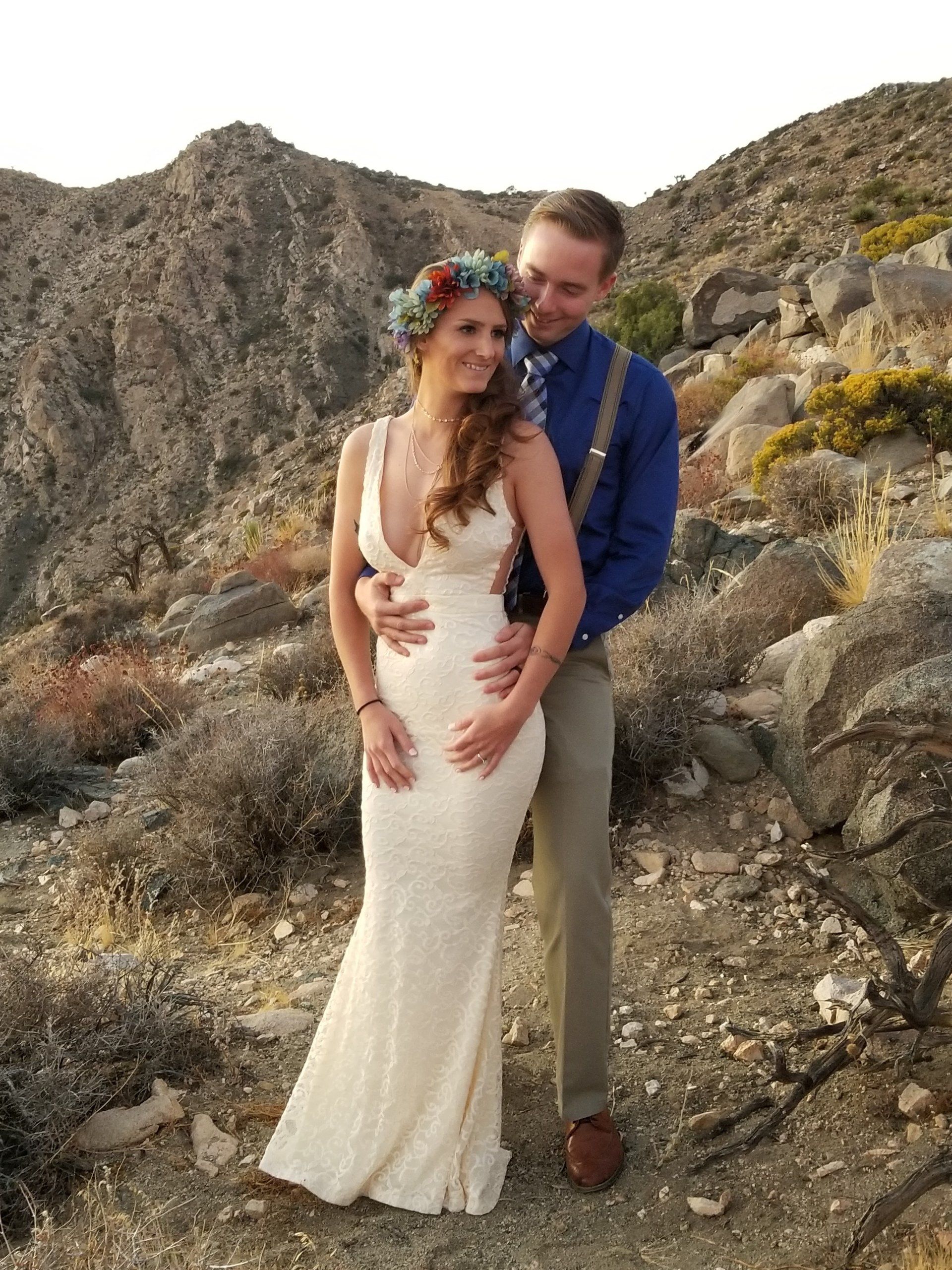 Bride with floral crown stand in front of her groom in this after ceremony photo at the Keys in Joshua Tree National Park