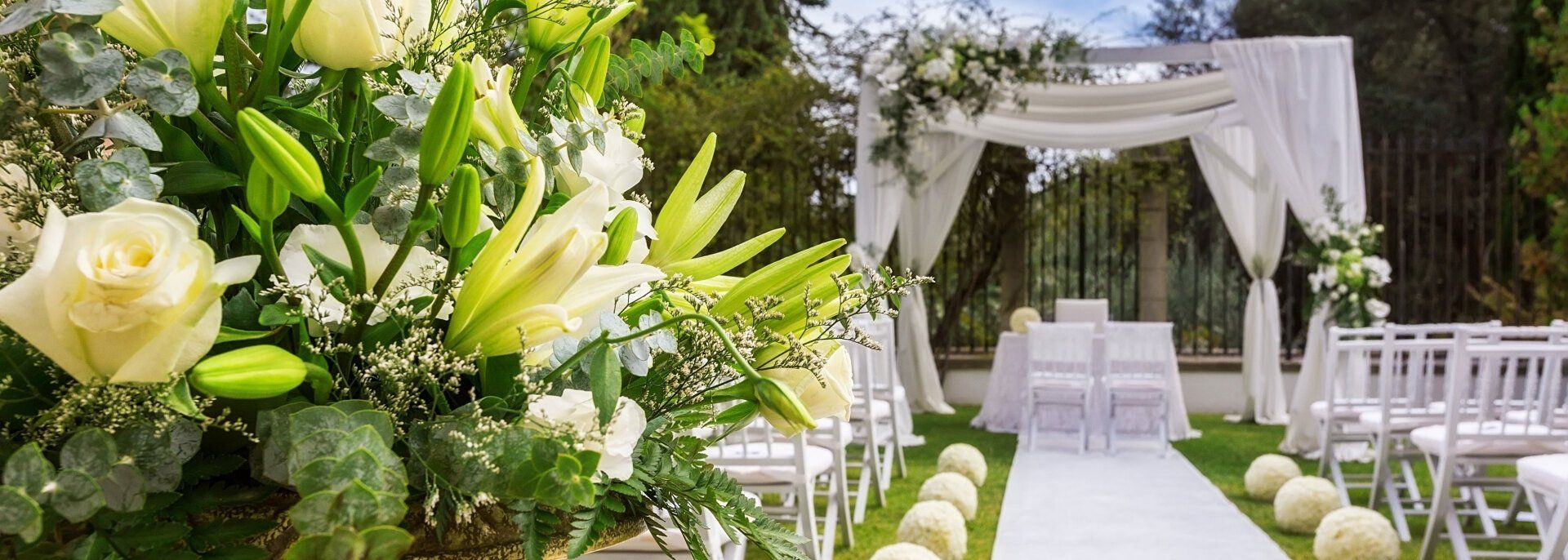 White and yellow themed flowers, chairs and center aisle of a wedding