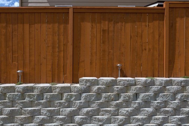 A wooden fence stands atop a stacked stone wall.