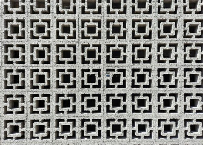 A detailed pattern of square blocks with geometric cutouts forms a repetitive grid.