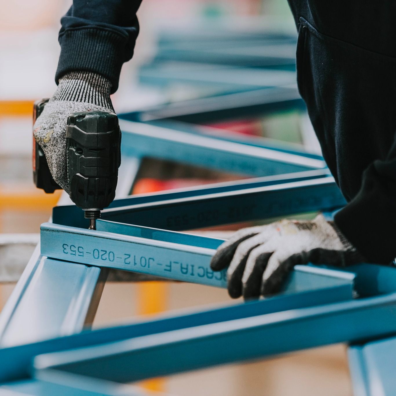 A Person Wearing Gloves is Working on a Piece of Metal — Steel Frame Company In Lithgow, NSW