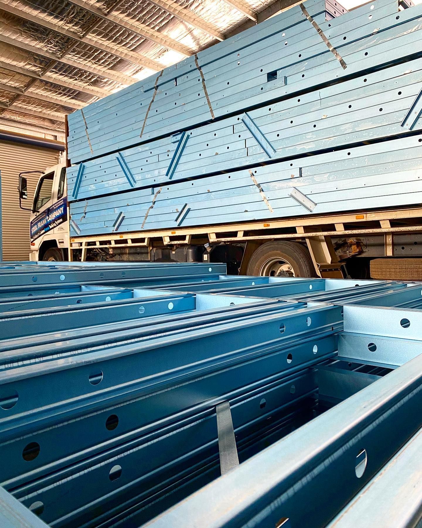 A Truck is Carrying a Stack of Blue Metal Beams in a Warehouse — Steel Frame Company In Mudgee, NSW