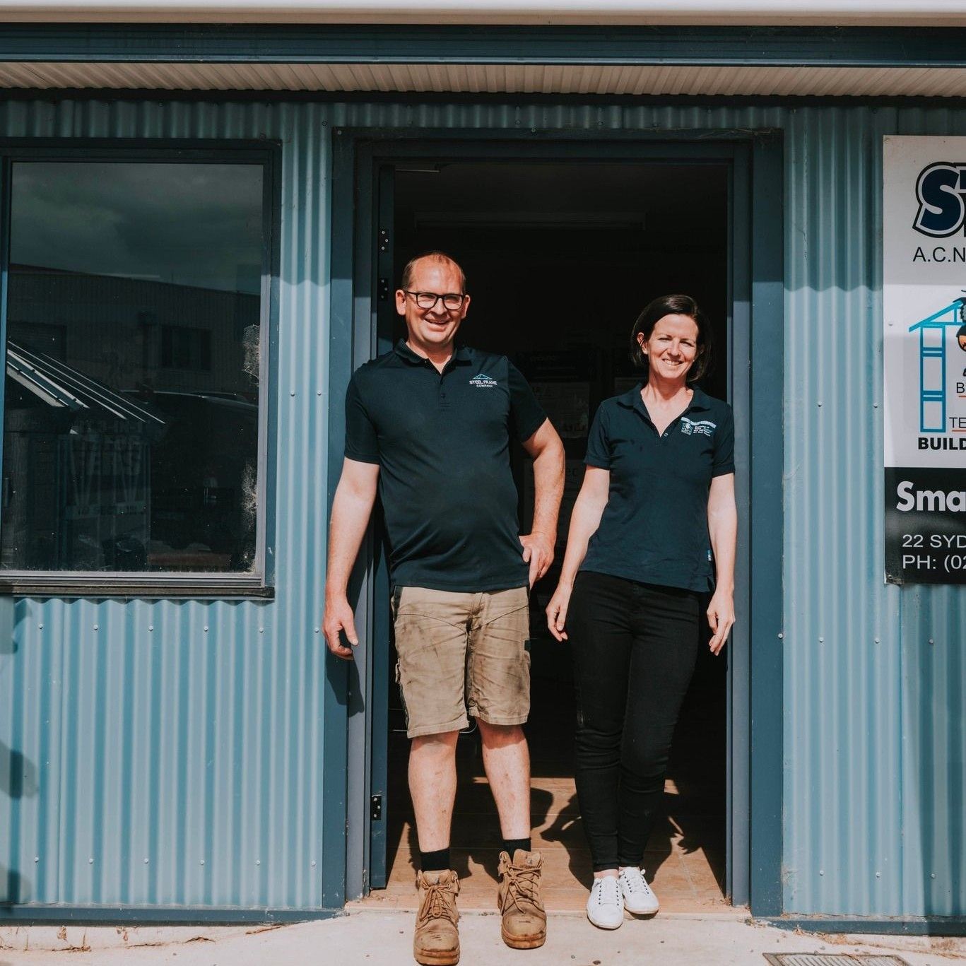 A Man and a Woman Are Standing in Front of a Building — Steel Frame Company In Mudgee, NSW