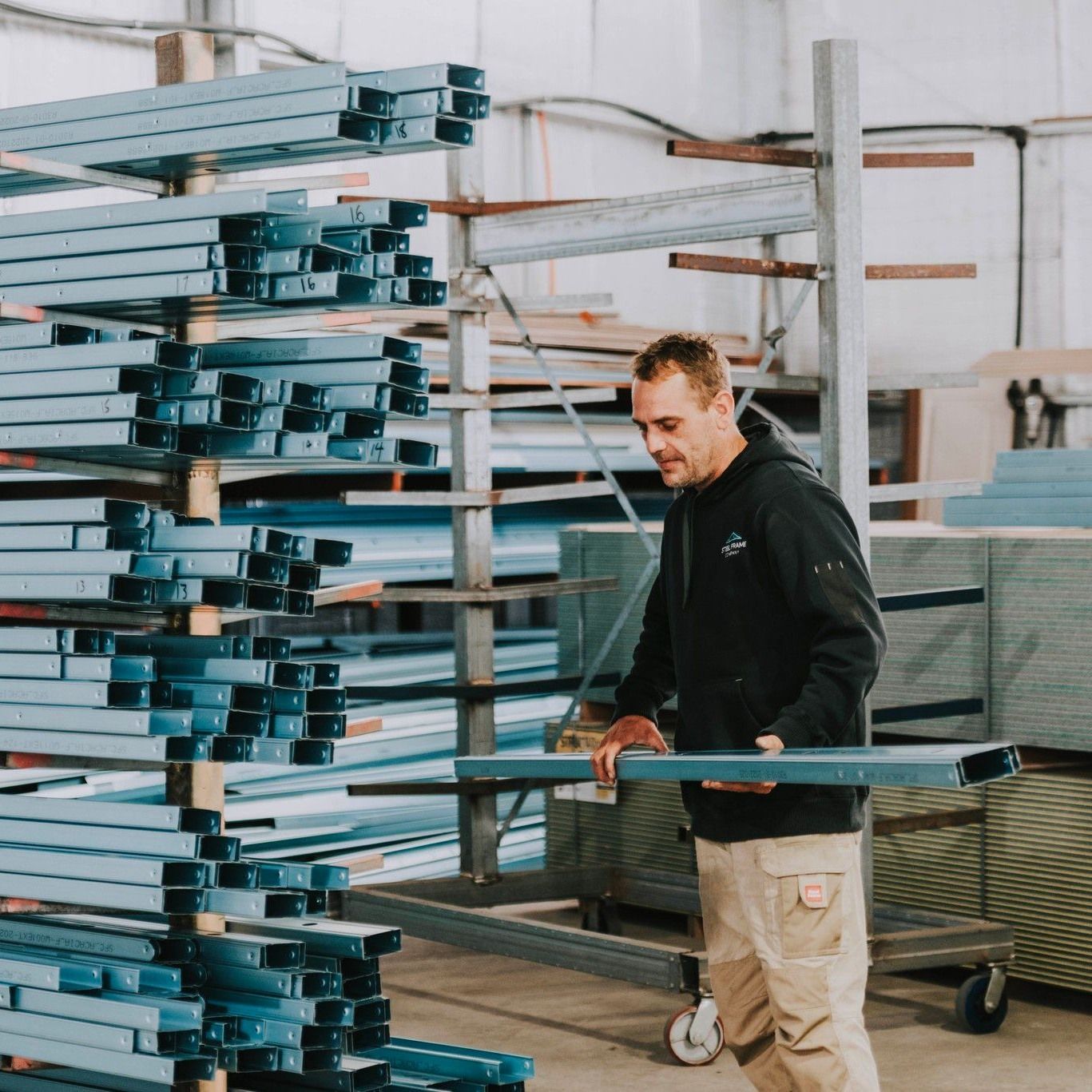 A Man is Standing in Front of a Stack of Blue Pipes — Steel Frame Company In Bathurst, NSW