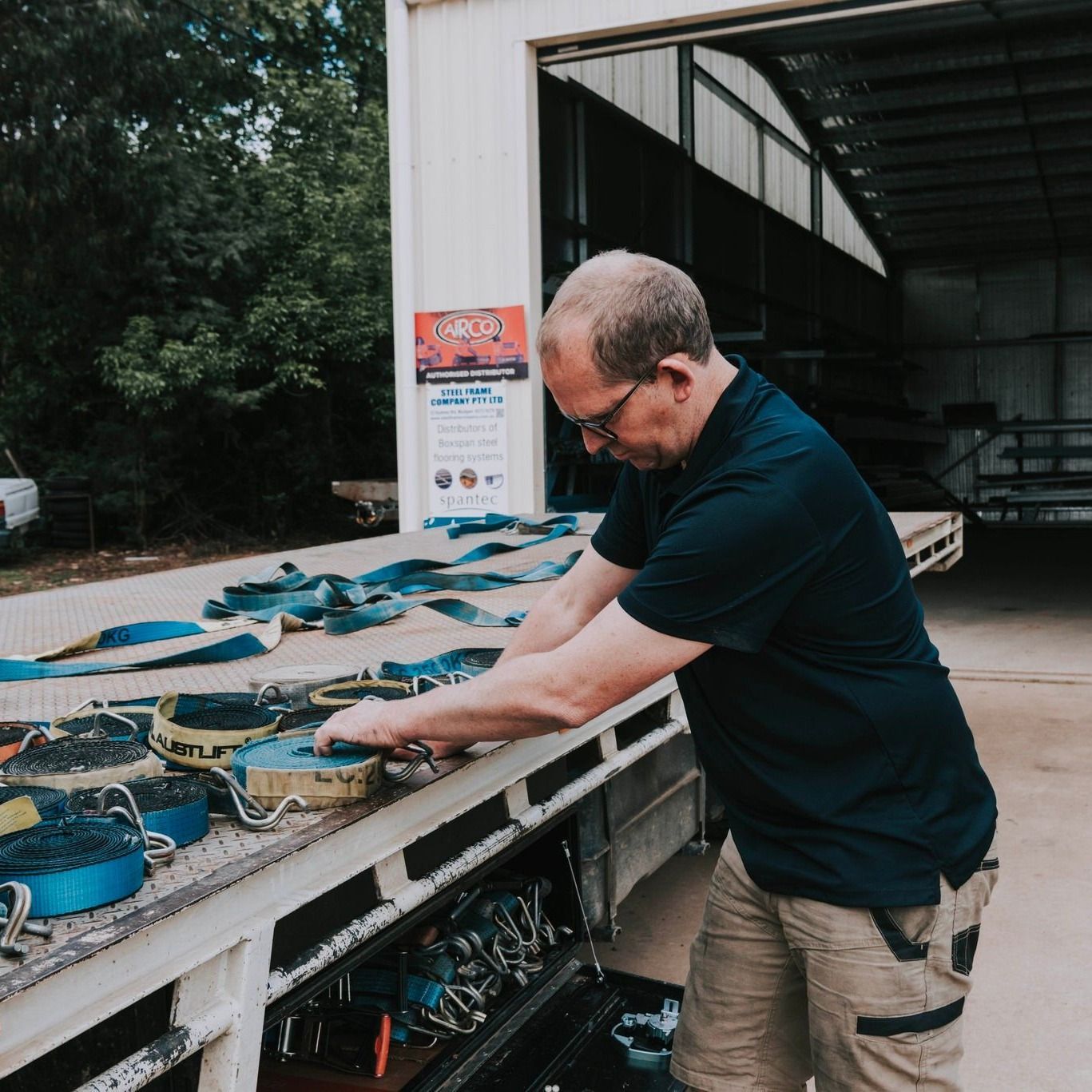 A Man in a Blue Shirt is Working on a Truck — Steel Frame Company In Coonabarabran, NSW