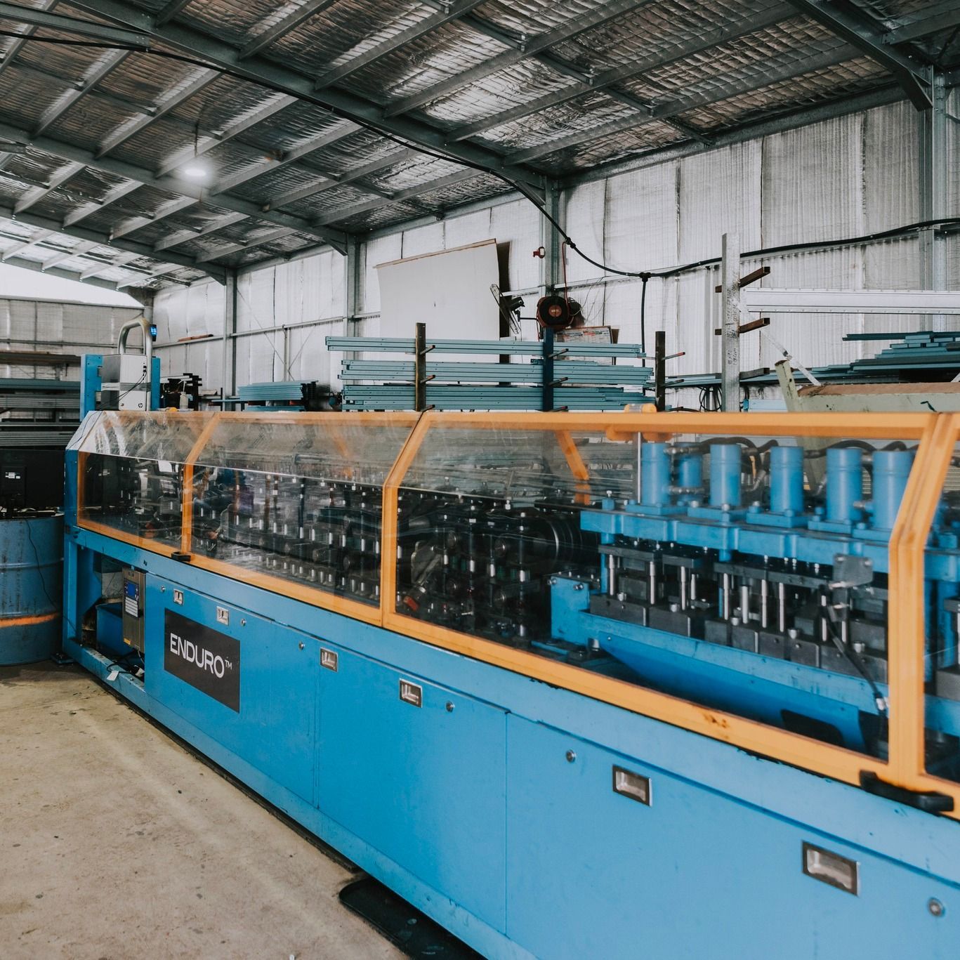 A Blue and Yellow Machine is Sitting in a Warehouse — Steel Frame Company In Mudgee, NSW