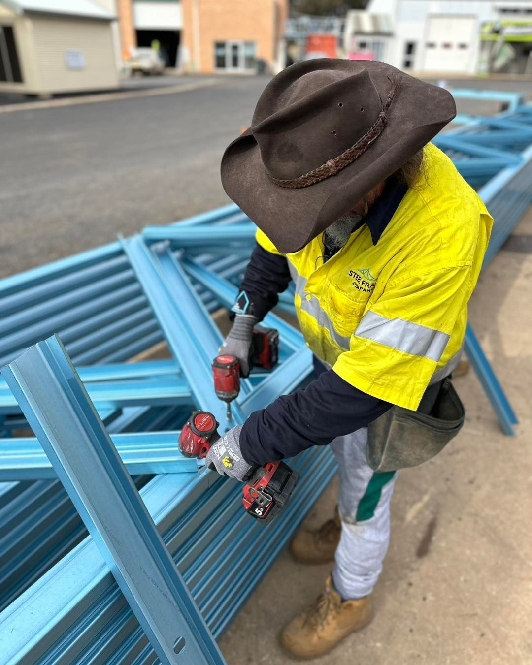 A Man is Using a Drill on a Metal Structure — Steel Frame Company In Mudgee, NSW