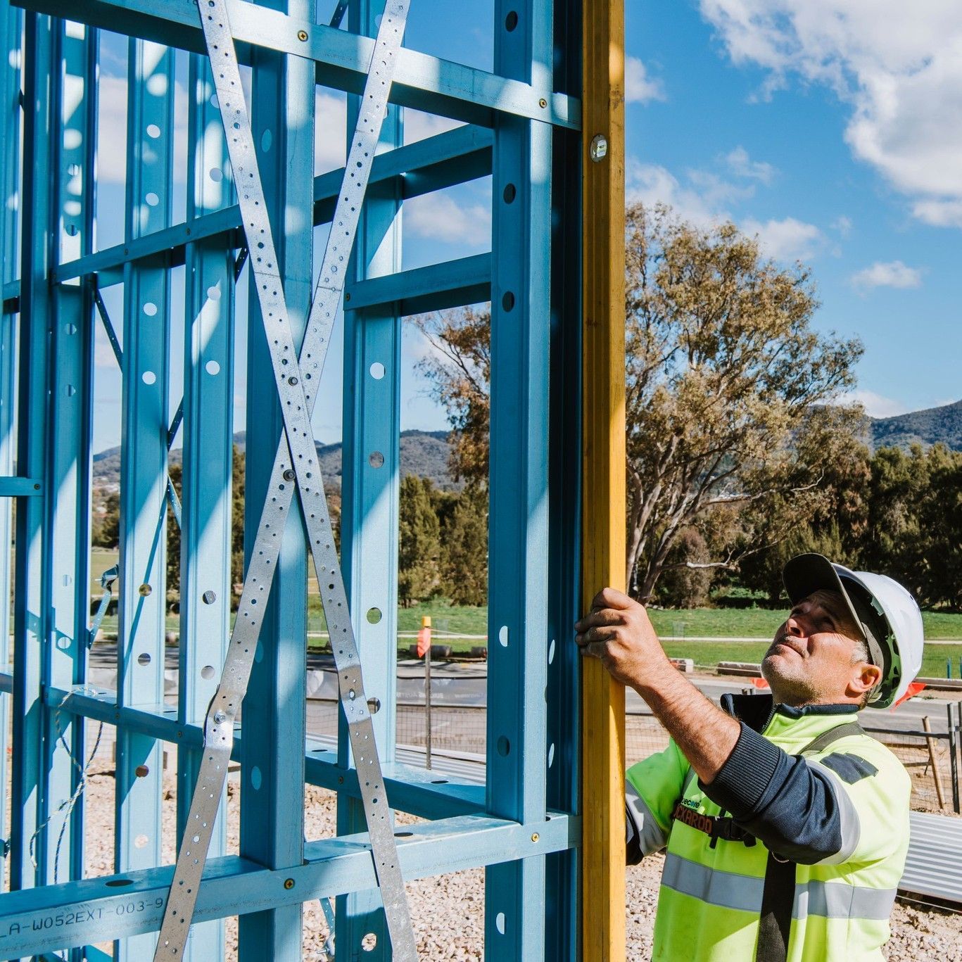 A Construction Worker is Measuring a Wall With a Tape Measure — Steel Frame Company In Mudgee, NSW