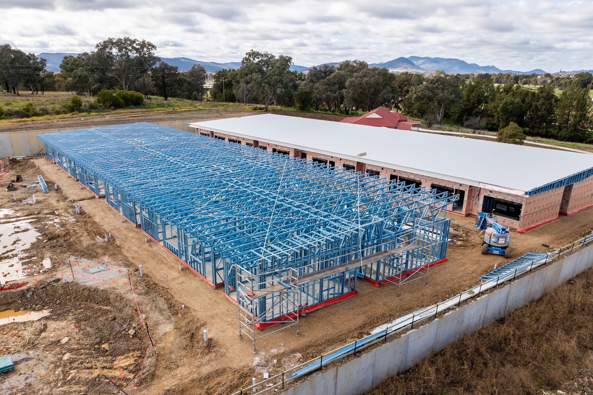 A large building is being built in the middle of a dirt field.