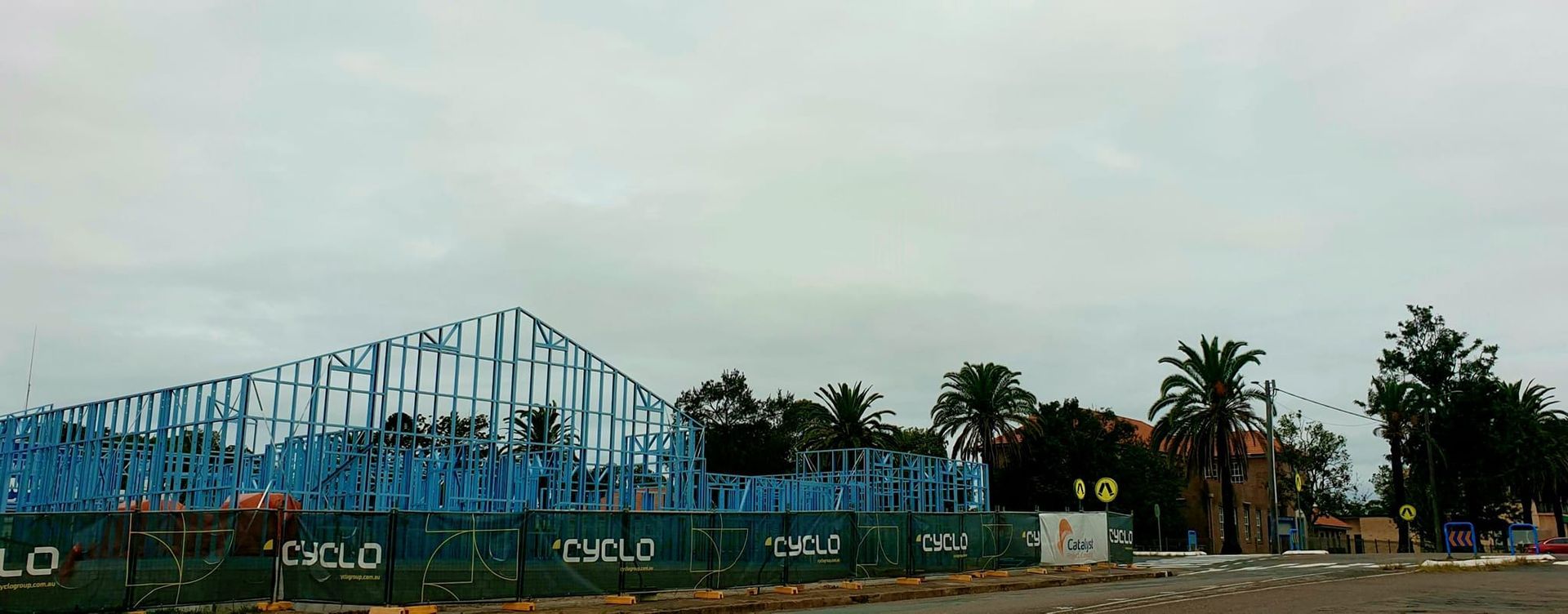 A roller coaster is being built in the middle of a fenced in area.