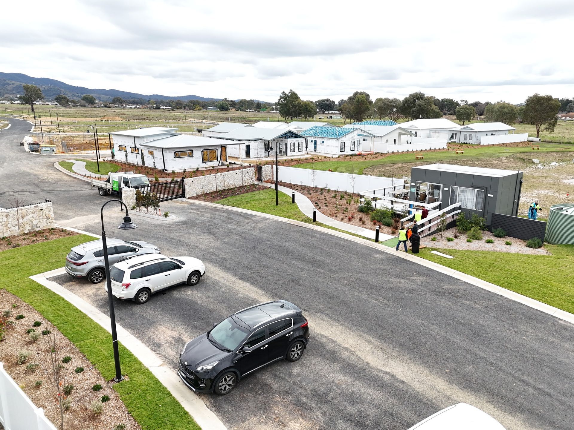 An aerial view of a residential area with cars parked on the side of the road.