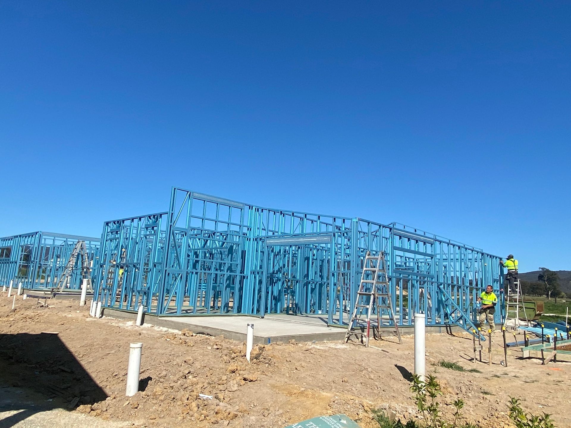A large building is being built in the middle of a dirt field.