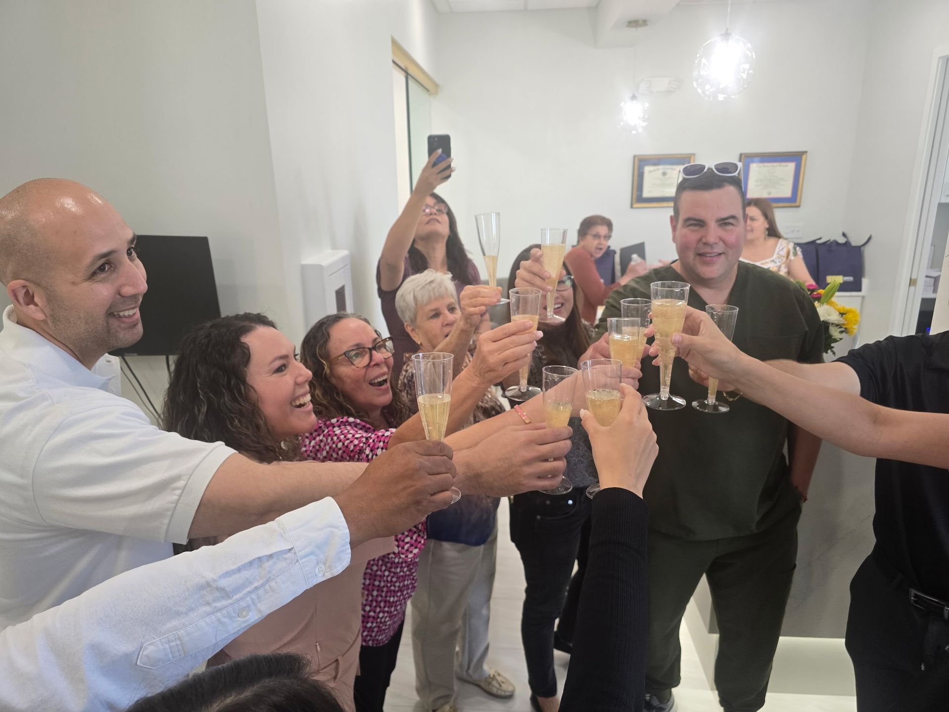 Group of people toasting with champagne flutes in a bright office setting; celebrating.