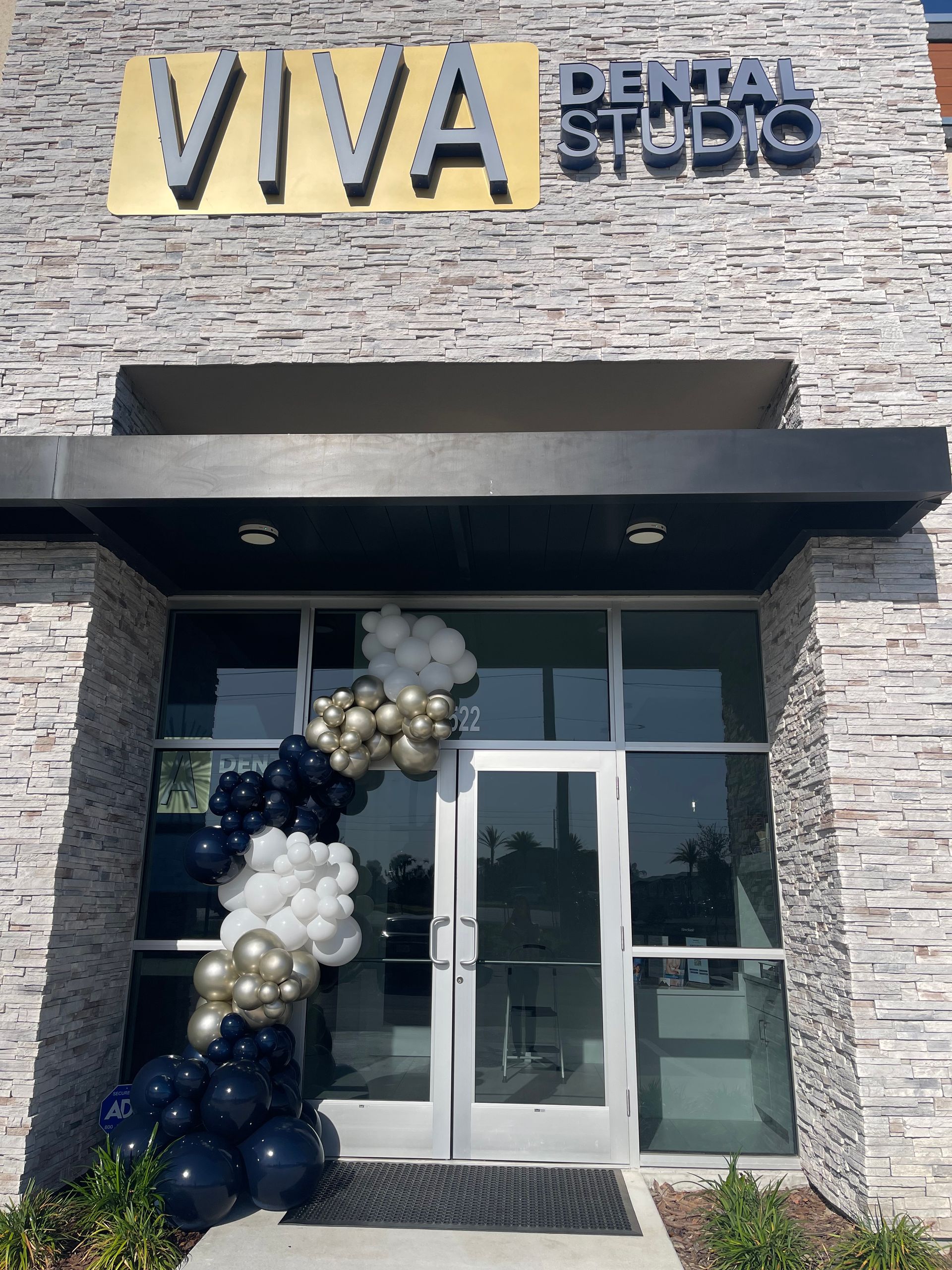 The entrance to Viva Dental Studio with a balloon arch and a stone facade.