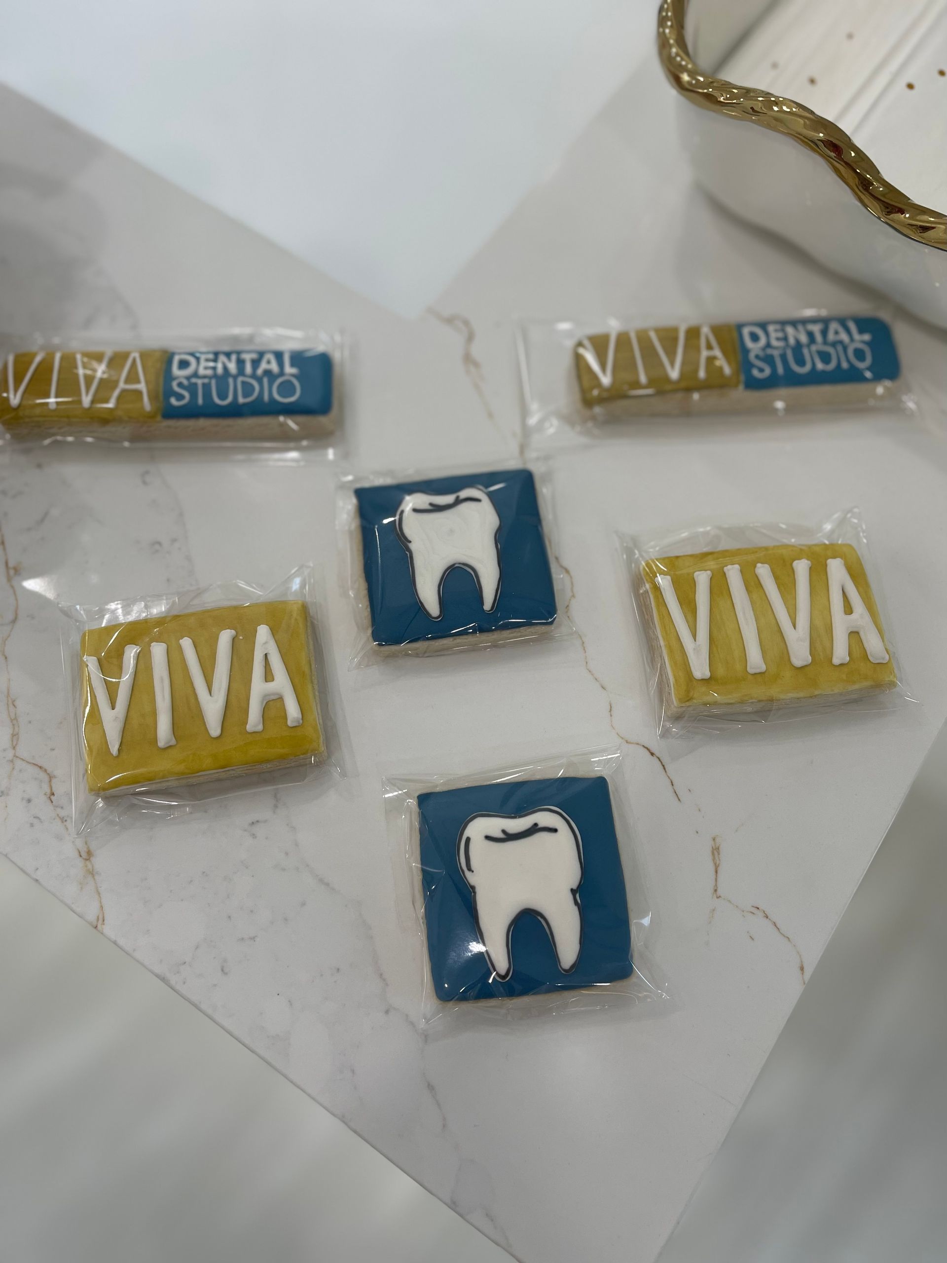 Cookies with dental studio logo in yellow and blue packaging.