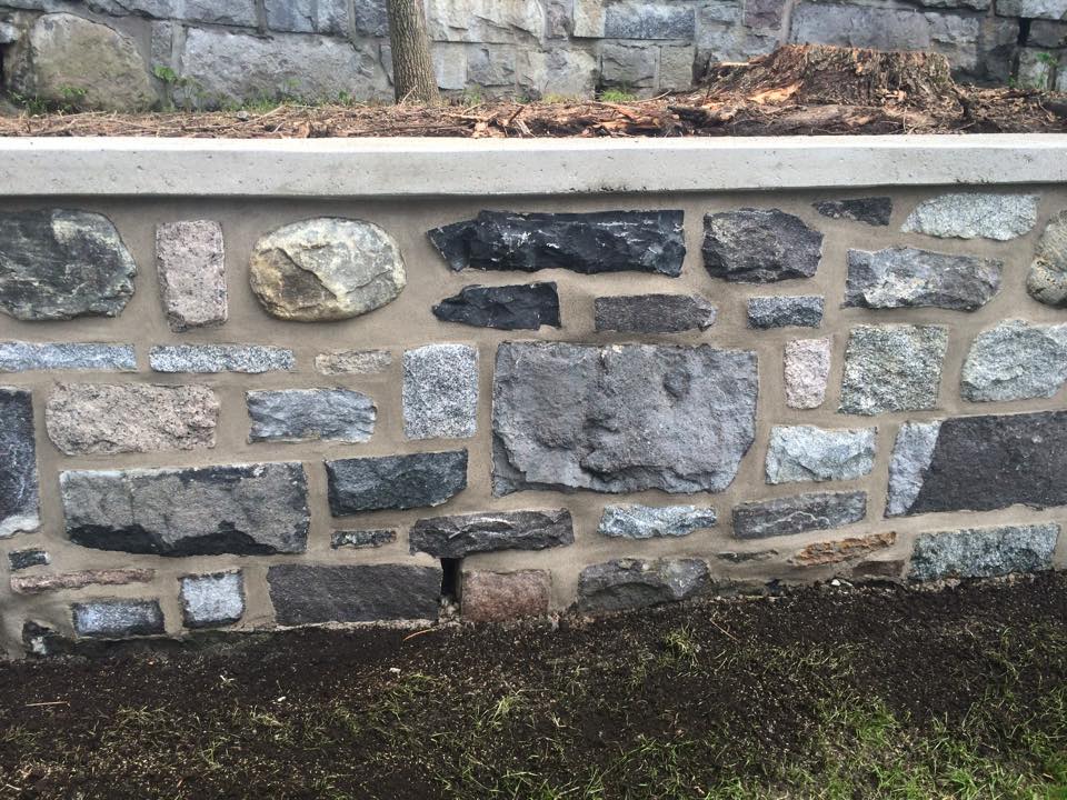 Un mur de pierre est entouré d'herbe et de terre