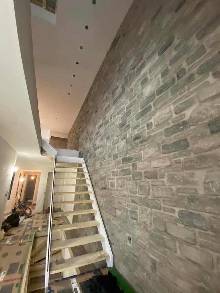 Un escalier est en cours de construction devant un mur de briques.