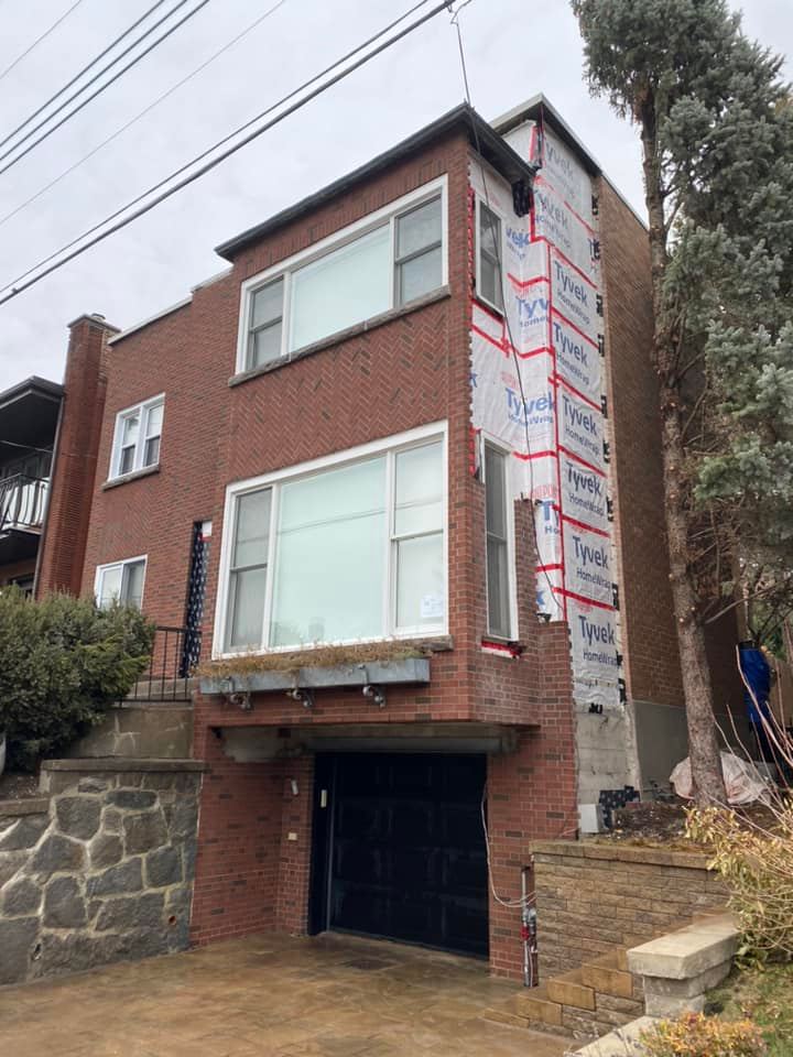 Une maison en brique avec un garage en dessous est en cours de rénovation.