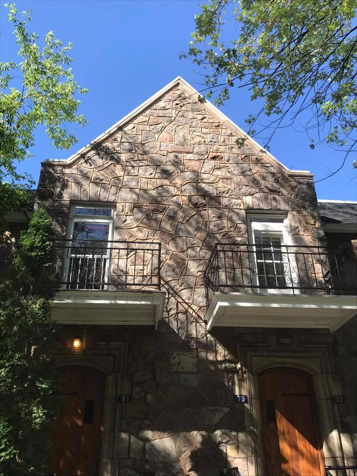 Une grande bâtisse en pierre avec balcon et escalier