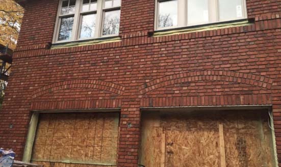 Un bâtiment en brique avec une porte de garage barricadée.