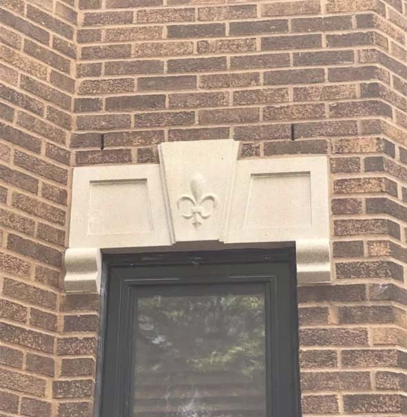 Un bâtiment en brique avec une fenêtre et une fleur de lys dessus