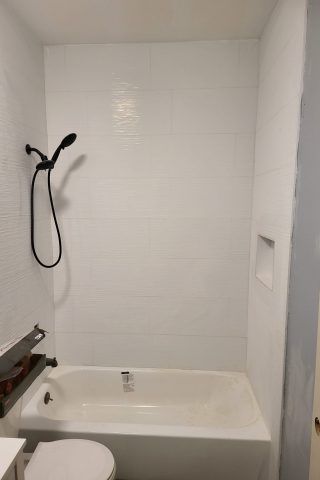 A bathroom with a bathtub , toilet and shower.