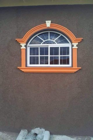A window with an orange frame is on a brown wall.