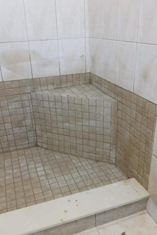 A bathroom with a tiled shower stall and steps.