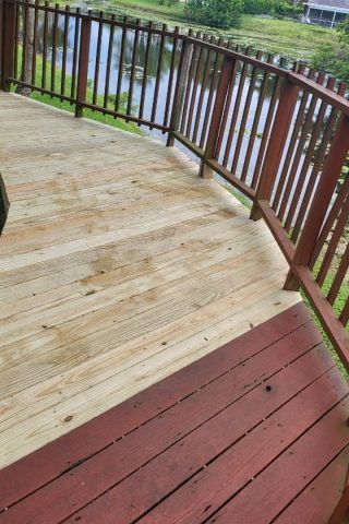 A wooden deck with a railing overlooking a body of water.