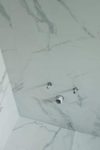 A close up of a ceiling in a bathroom with marble tiles.
