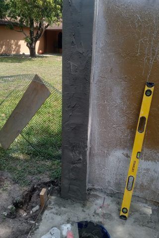 A yellow level is sitting next to a concrete post.