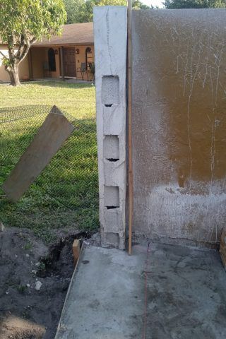 A concrete wall is being built in the backyard of a house.