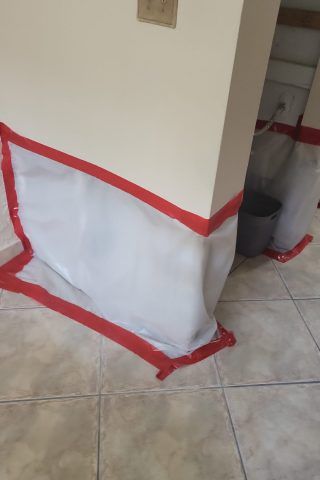 A white tarp is covering a corner of a wall in a room.