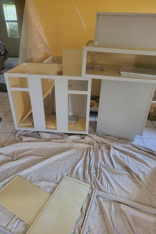 A kitchen cabinet is being painted in a living room.