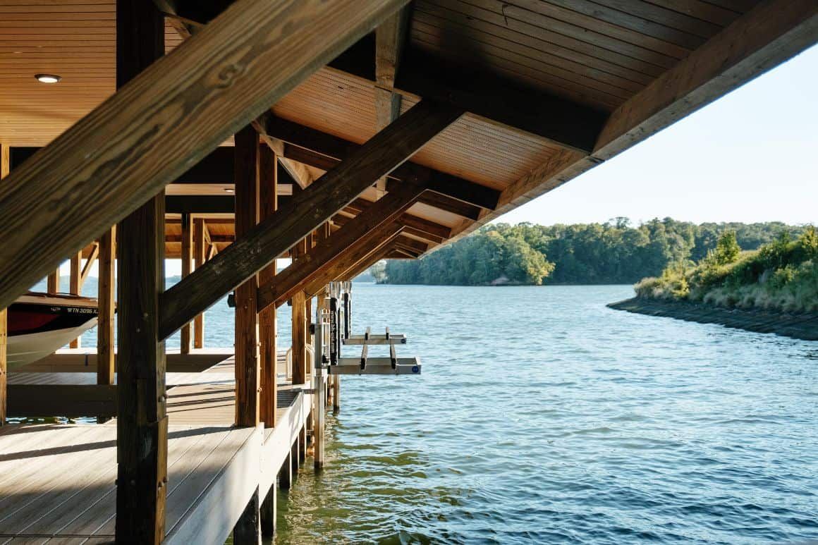 A boat is docked under a wooden structure next to a body of water.