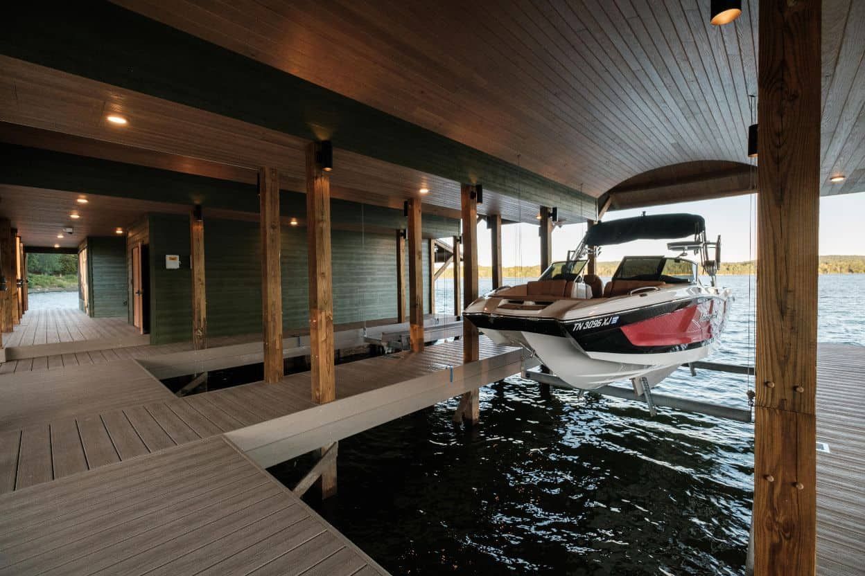 A boat is sitting under a dock on a lake.