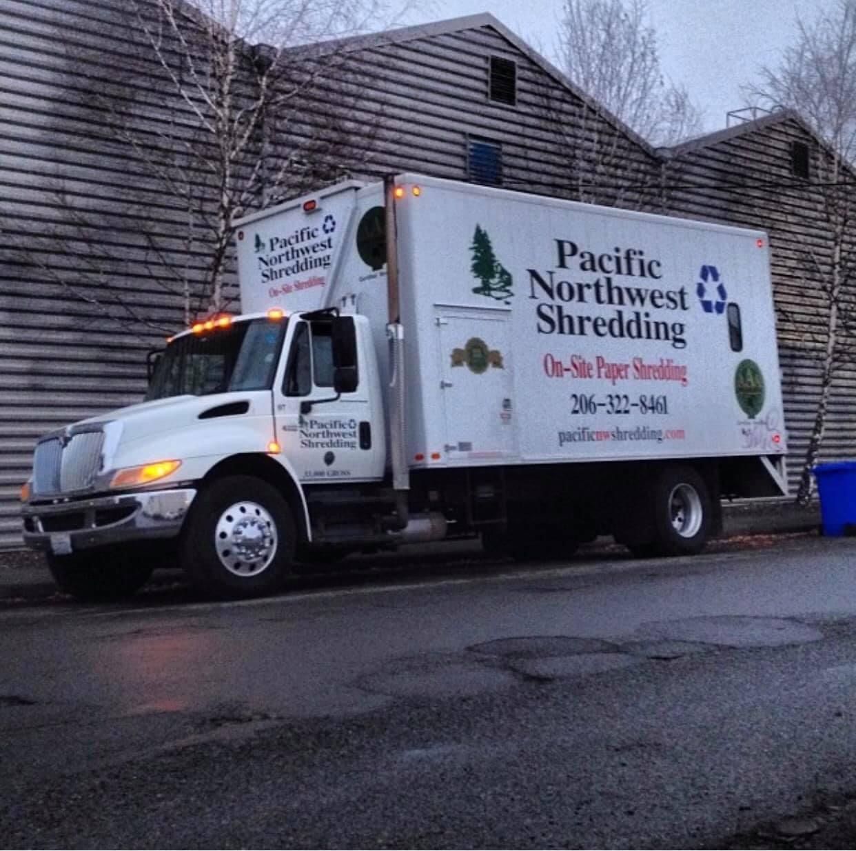 A pacific northwest shredding truck is parked in front of a building