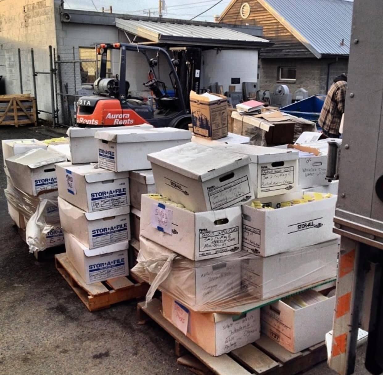 A bunch of boxes are stacked on top of each other with a forklift in the background