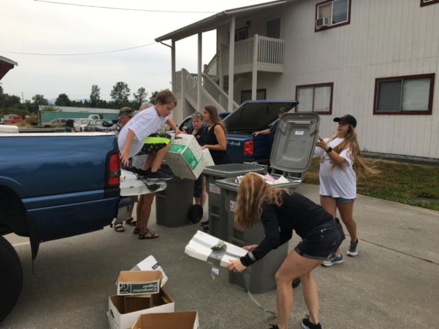 A group of people are loading trash cans into a truck